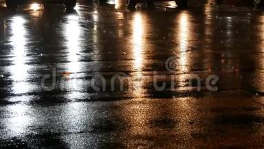 行人在夜间穿过街道，雨中镜头耀斑击中摄影师的背景。 城市生活。